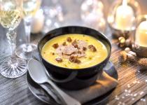 Photo d'un bol de velouté de potiron avec des copeaux de foie-gras posé sur une table